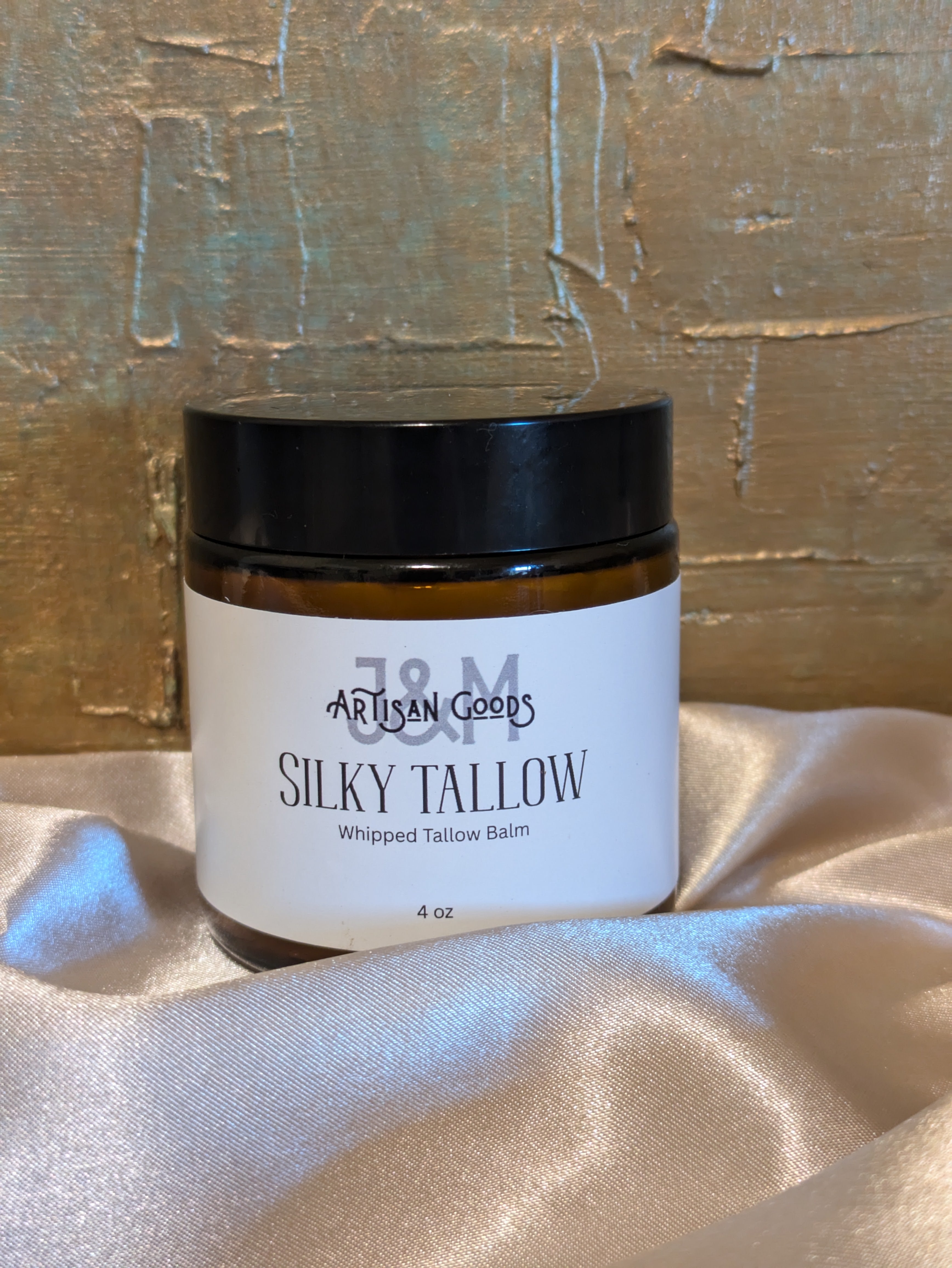Jar of 'Silky Tallow' whipped balm on a textured surface with a gold background